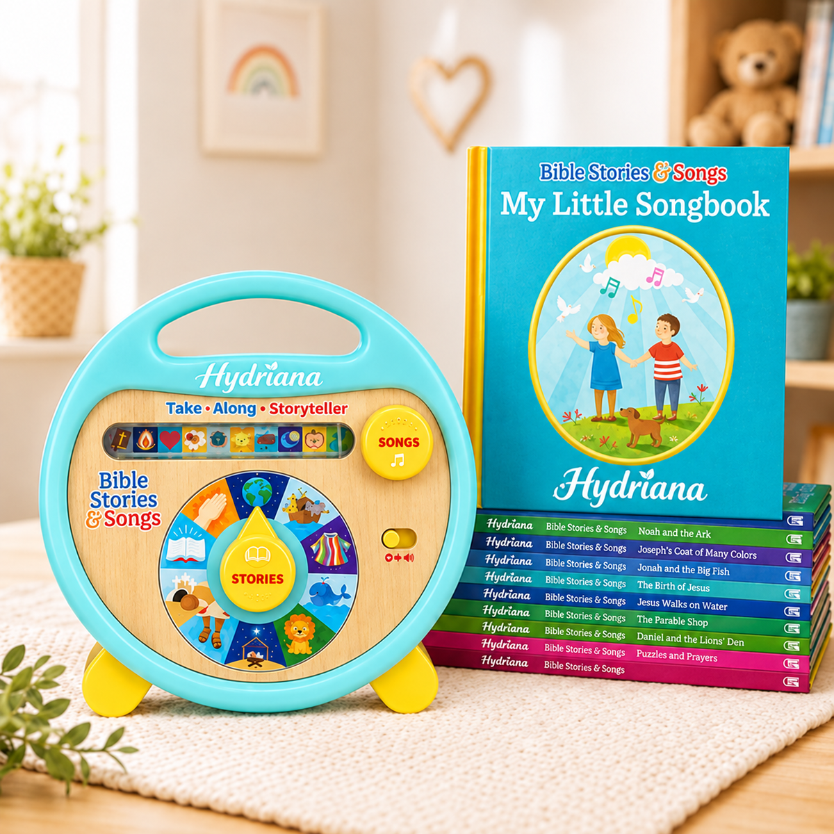 A children's Hydrana Bible Stories & Songs toy set shown in a styled indoor room. The set includes a turquoise and wood storytime speaker with a colorful dial, a hardcover songbook titled 'My Little Songbook,' and a stack of matching songbook covers in bright colors.